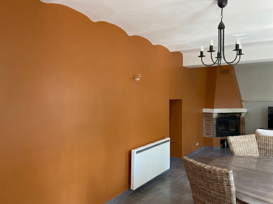 Salon avec mur en terre cuite orangée, joint plafond en forme de vagues