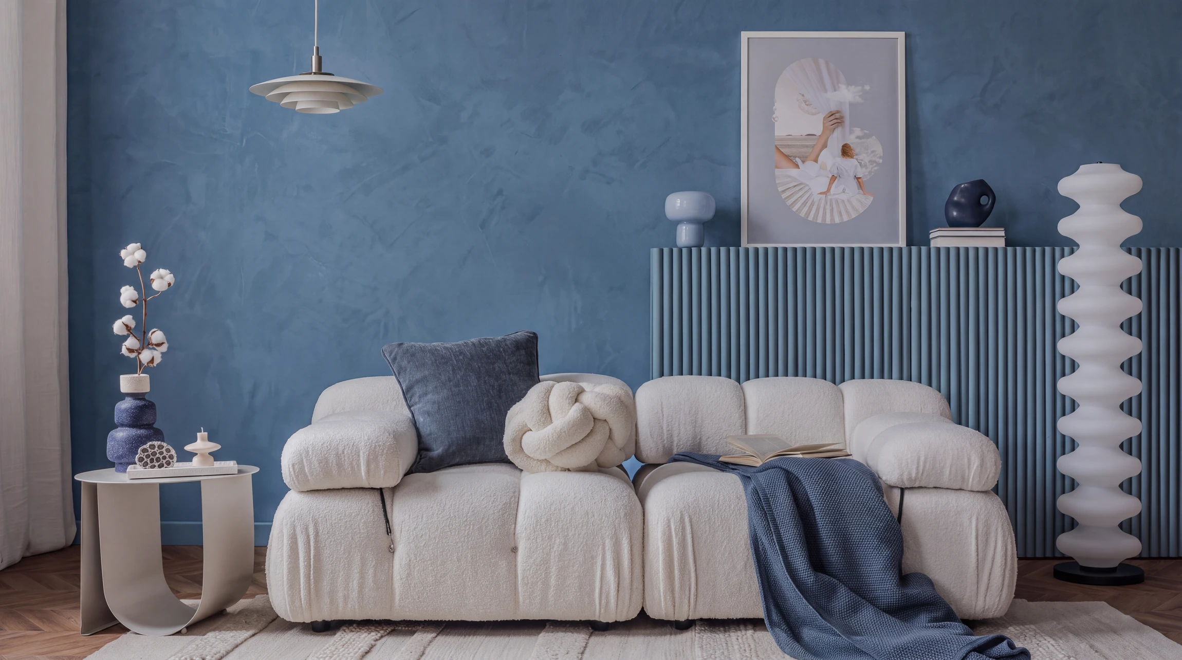 Une personne applique un enduit ou une pâte de rebouchage sur un mur intérieur blanc à l'aide d'une spatule professionnelle