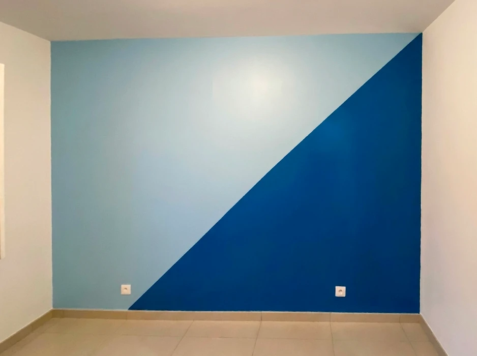 Mur d'accent peint en deux tons de bleu séparés par une ligne diagonale nette : bleu ciel clair en partie supérieure gauche, bleu roi intense en partie inférieure droite